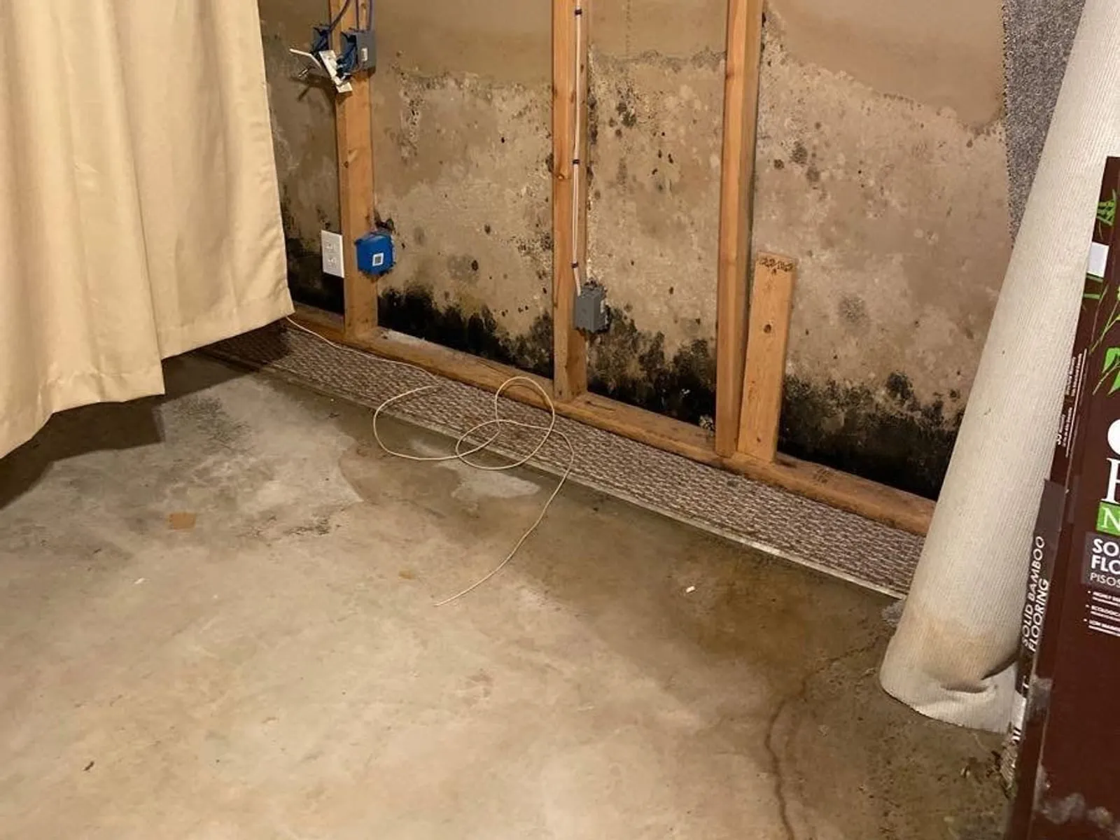 Basement floor with drying equipment set up against the foundation