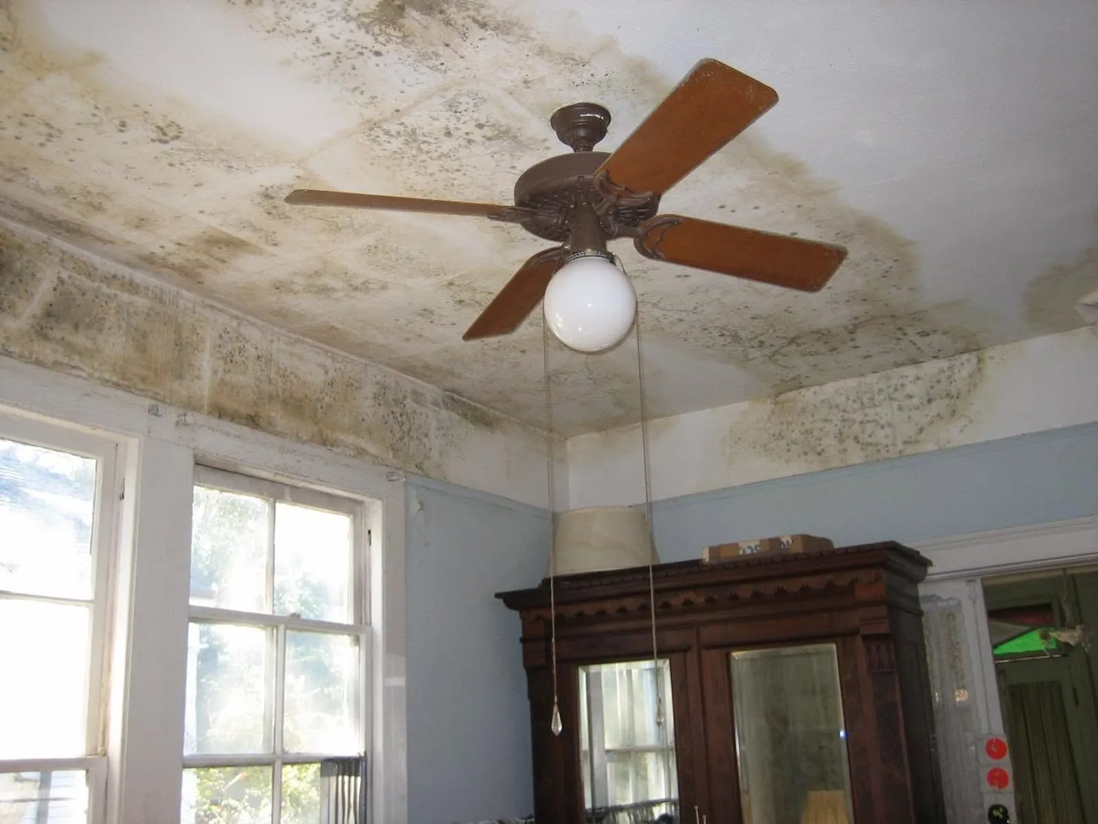 Ceiling with dark staining spreading out from a fan
